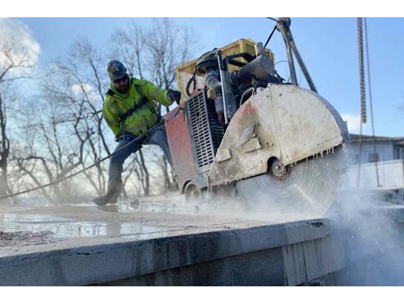 Walk behind concrete saw cutting an outdoor concrete surface
